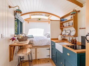 Eine kleine Küche mit eingebautem Herd, Holzbarhocker und einer Frühstückstheke.