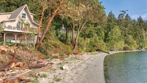 A house with a balcony, a gravel path, and a forested area beside a body of water. - WM BLOCK Deer Harbor 1br (Deer Harbor)