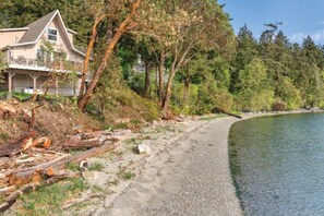 A house with a balcony, a gravel path, and a forested area beside a body of water. - WM BLOCK Deer Harbor 1br (Deer Harbor)