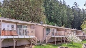 A row of single-story cabins with balconies, surrounded by a well-maintained lawn and dense forest. - WM BLOCK Deer Harbor 1br (Deer Harbor)