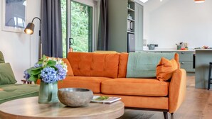 Ein modernes Wohnzimmer mit einer Couch, einem runden Holztisch und einer Blumenvase.