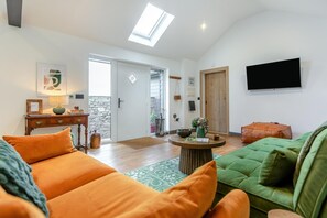 A spacious living area with a sofa, a coffee table, and a television mounted on the wall. - 1 Bed in Eggesford (oc-l45452) (Wembworthy)