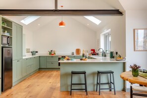 A modern kitchen with a central island, wooden flooring, and a skylight. - 1 Bed in Eggesford (oc-l45452) (Wembworthy)