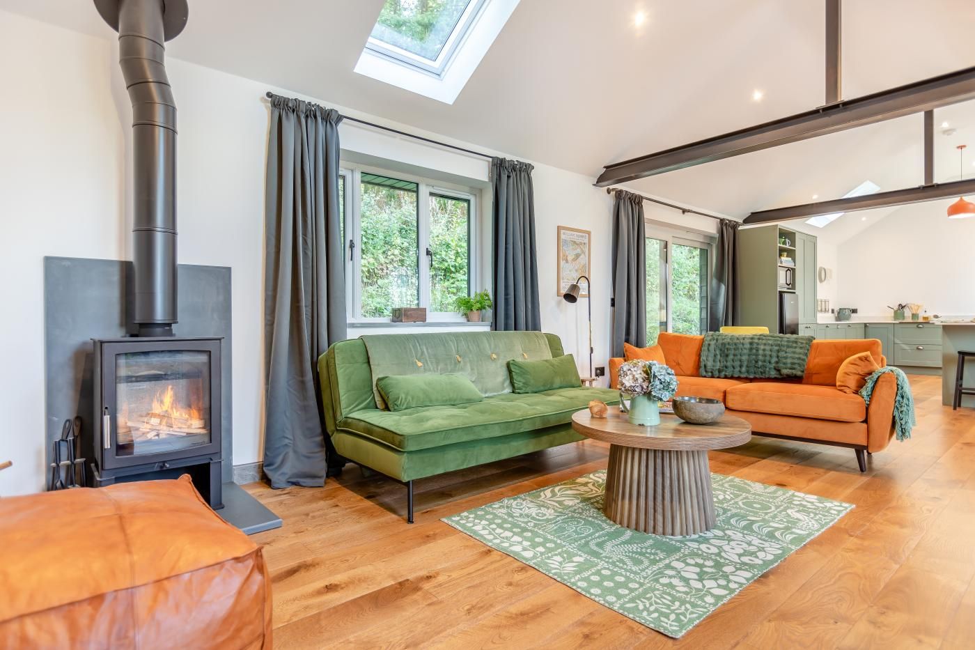 A modern living room with a wood-burning stove, two sofas, a coffee table, and a skylight.