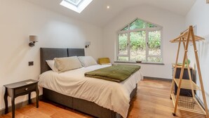 Ein Schlafzimmer mit Bett, Nachttisch, Fenster und Oberlicht.