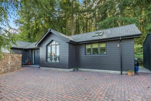 A modern house with a brick driveway, a stone wall, and a large window. - 1 Bed in Eggesford (oc-l45452) (Wembworthy)