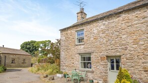 A stone house with a paved driveway, a small patio with a chair, and potted plants. - 2 Bed in Appersett (oc-d45772) (Appersett)