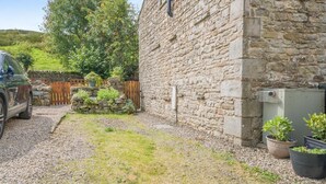 A stone building with a gravel driveway, a parked car, and potted plants. - 2 Bed in Appersett (oc-d45772) (Appersett)
