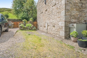 A stone building with a gravel driveway, a parked car, and potted plants. - 2 Bed in Appersett (oc-d45772) (Appersett)
