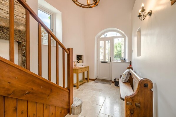 A wooden staircase leading to a room with a bench, a desk, and a door with a window.