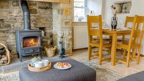 A cozy living room with a stone fireplace, a dining table with chairs, and a sofa. - 2 Bed in Appersett (oc-d45772) (Appersett)