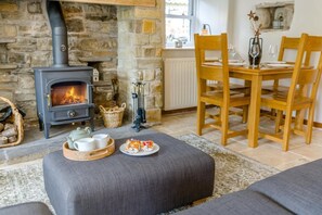 A cozy living room with a stone fireplace, a dining table with chairs, and a sofa. - 2 Bed in Appersett (oc-d45772) (Appersett)