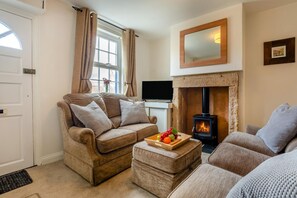 A cozy living room with a sofa, ottoman, and a fireplace. - 2 Bed in Cockermouth (oc-b44967) (Cockermouth)