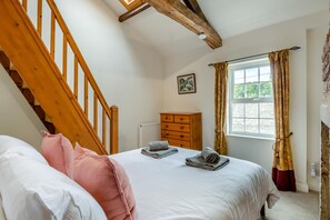 A bedroom with a wooden staircase, a bed with pillows, a dresser, and a window with curtains. - 2 Bed in Cockermouth (oc-b44967) (Cockermouth)