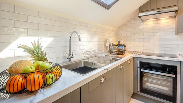 Una cocina moderna con tragaluz, electrodomésticos de acero inoxidable y un frutero sobre la encimera.