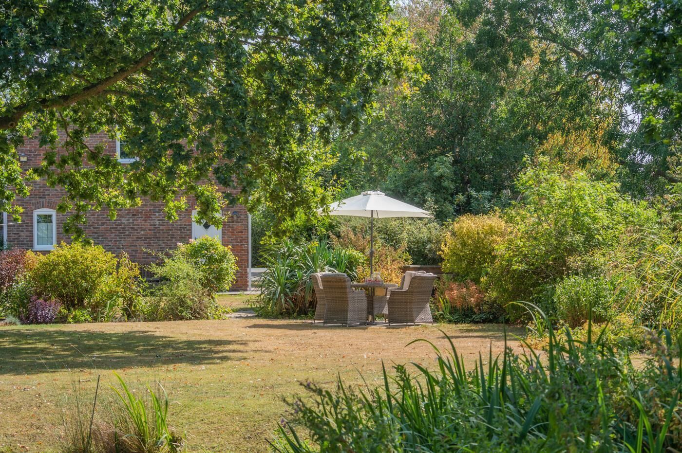 Ein Garten mit einem Backsteinhaus, Gartenmöbeln und verschiedenen Pflanzen.