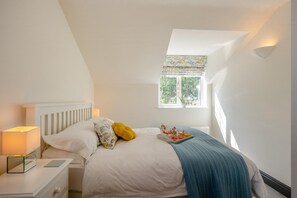 Ein Schlafzimmer mit Bett, Nachttisch, Lampe, Fenster und einem Tablett mit Frühstück.