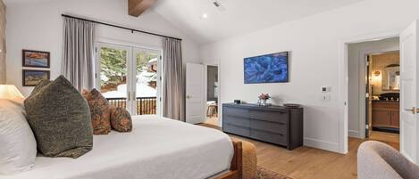 Ein geräumiges Schlafzimmer mit einem großen Bett, einem Deckenventilator und Blick ins Freie durch eine Schiebetür.