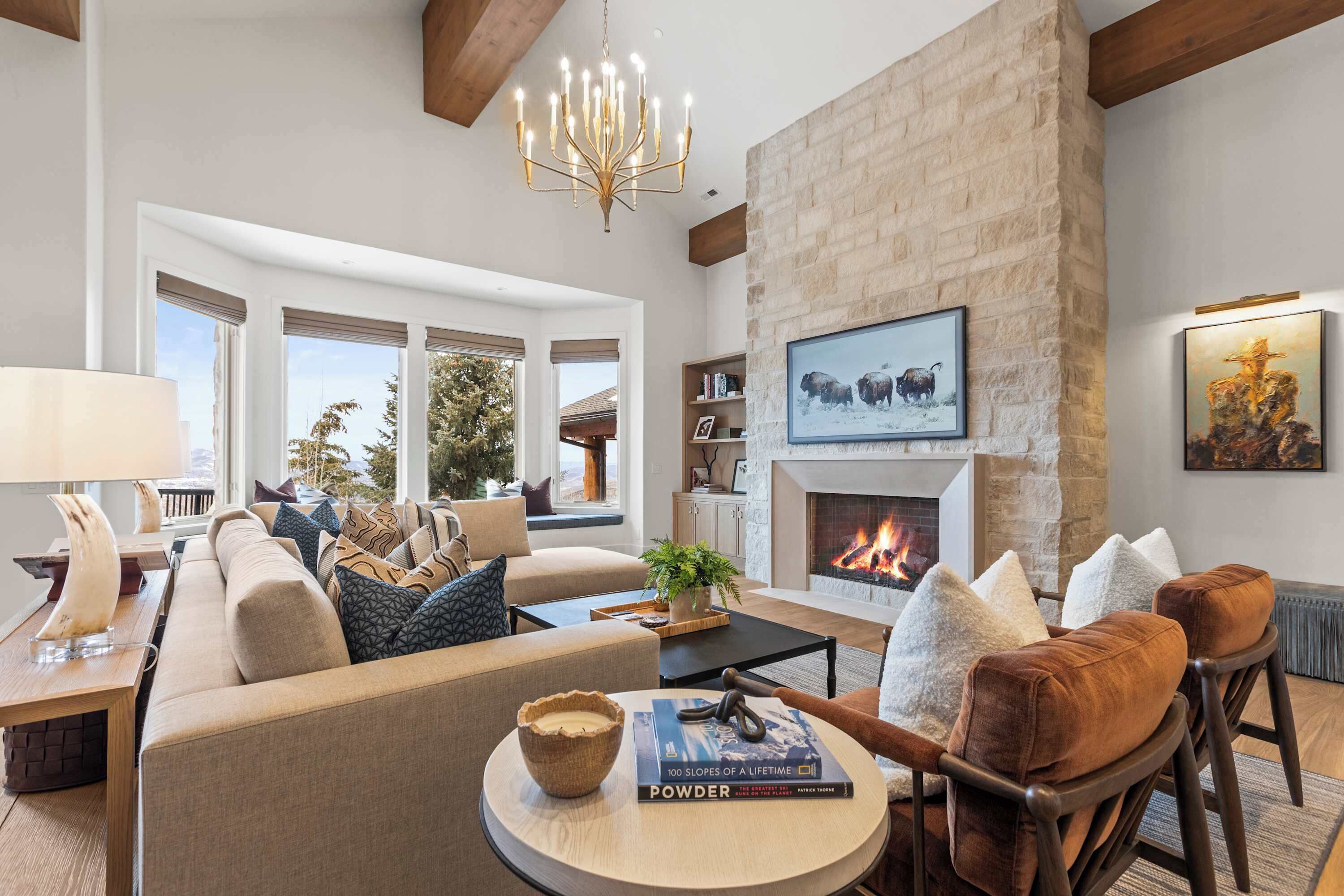 A spacious living room with a fireplace, comfortable seating, and a large window offering a view of the outdoors.