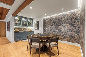 A dining area with a round table and chairs, a kitchen with cabinets and a countertop, and a patterned wall. - Abode at Sun Ridge, private hot tub, stunning interior, Deer Valley (Park City)