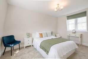 A bedroom with a bed, a chair, a nightstand, a dresser, and a window with curtains. - 2 Bed in Overstrand (oc-s45741) (Overstrand)
