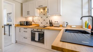 A modern kitchen with white cabinets, a wooden countertop, and a built-in oven. - 2 Bed in Overstrand (oc-s45741) (Overstrand)