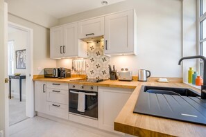 A modern kitchen with white cabinets, a wooden countertop, and a built-in oven. - 2 Bed in Overstrand (oc-s45741) (Overstrand)
