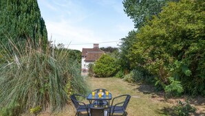 A patio with a table and chairs, surrounded by grass and various plants. - 2 Bed in Overstrand (oc-s45741) (Overstrand)