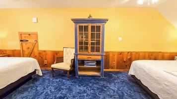 A room with two beds, a blue cabinet with glass doors, a chair, and a wooden door.