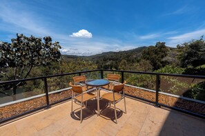 A terrace with a table and chairs, overlooking a mountainous landscape. - Hotel Piedras Blancas (Guarne)