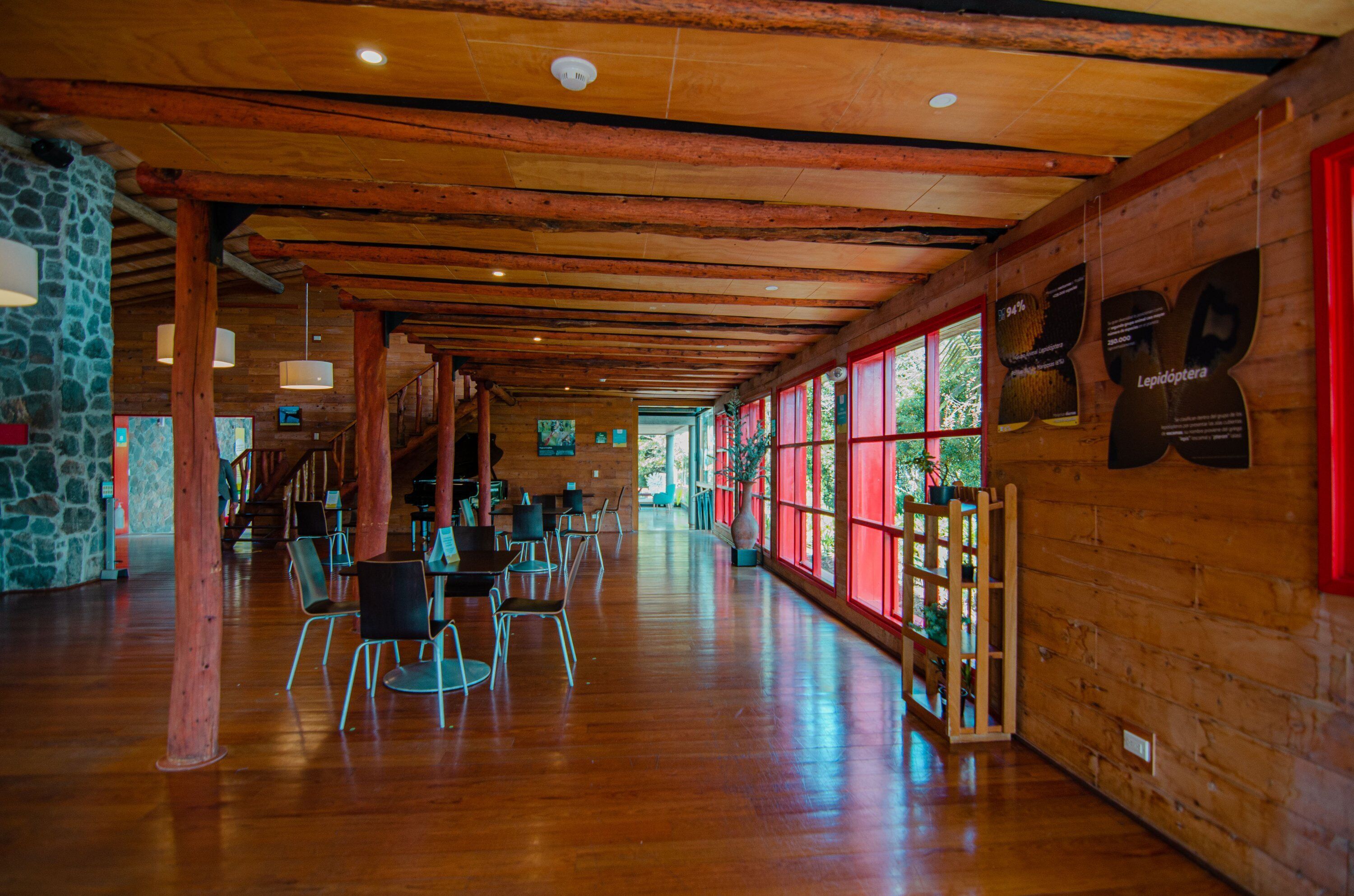 Amplio espacio interior con vigas de madera, paredes de piedra y ventanas grandes.