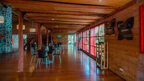 Um espaço amplo e interno com vigas de madeira, paredes de pedra e grandes janelas.