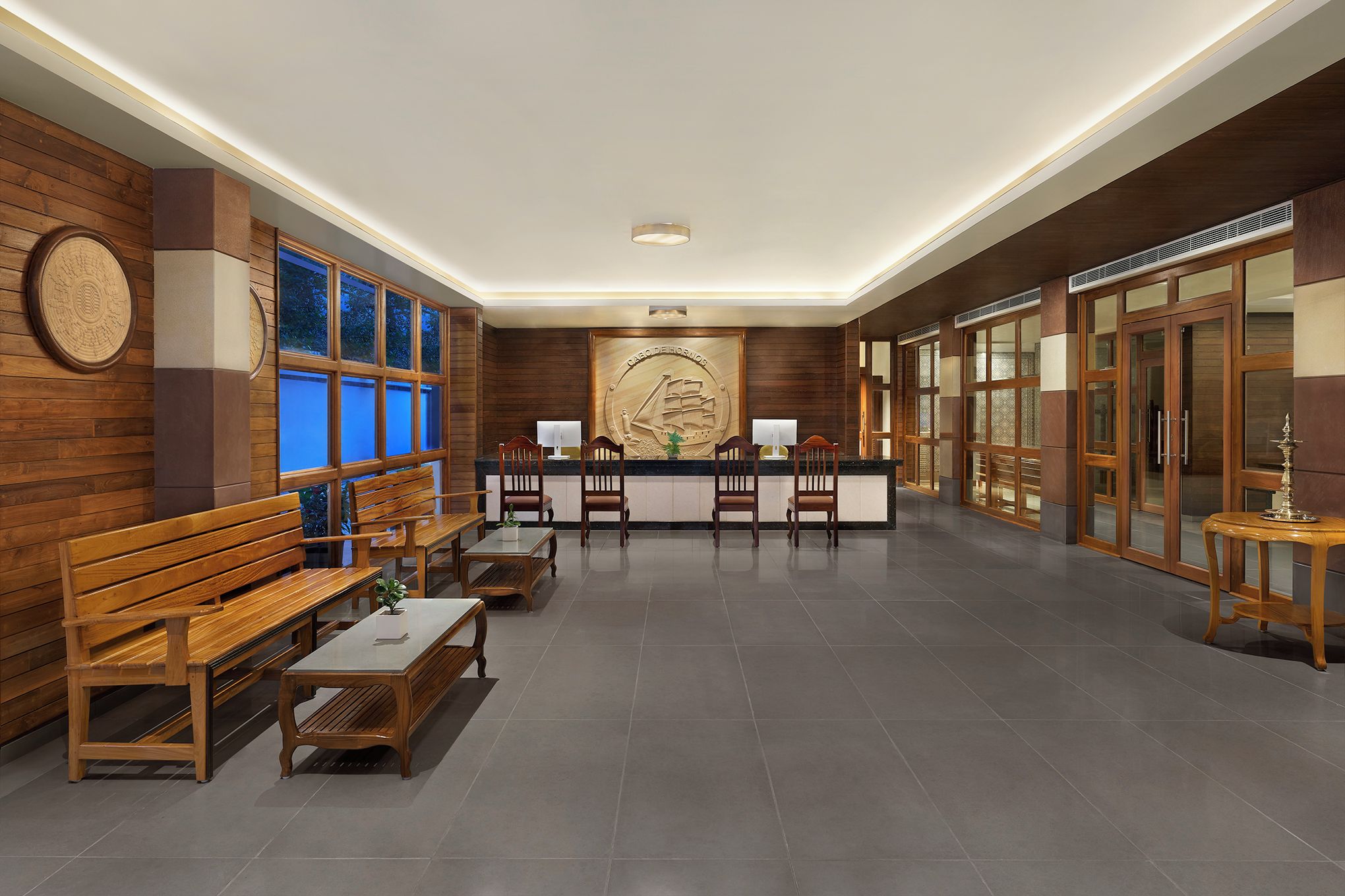 A reception area with wooden benches, a reception desk, and a large wall-mounted emblem.