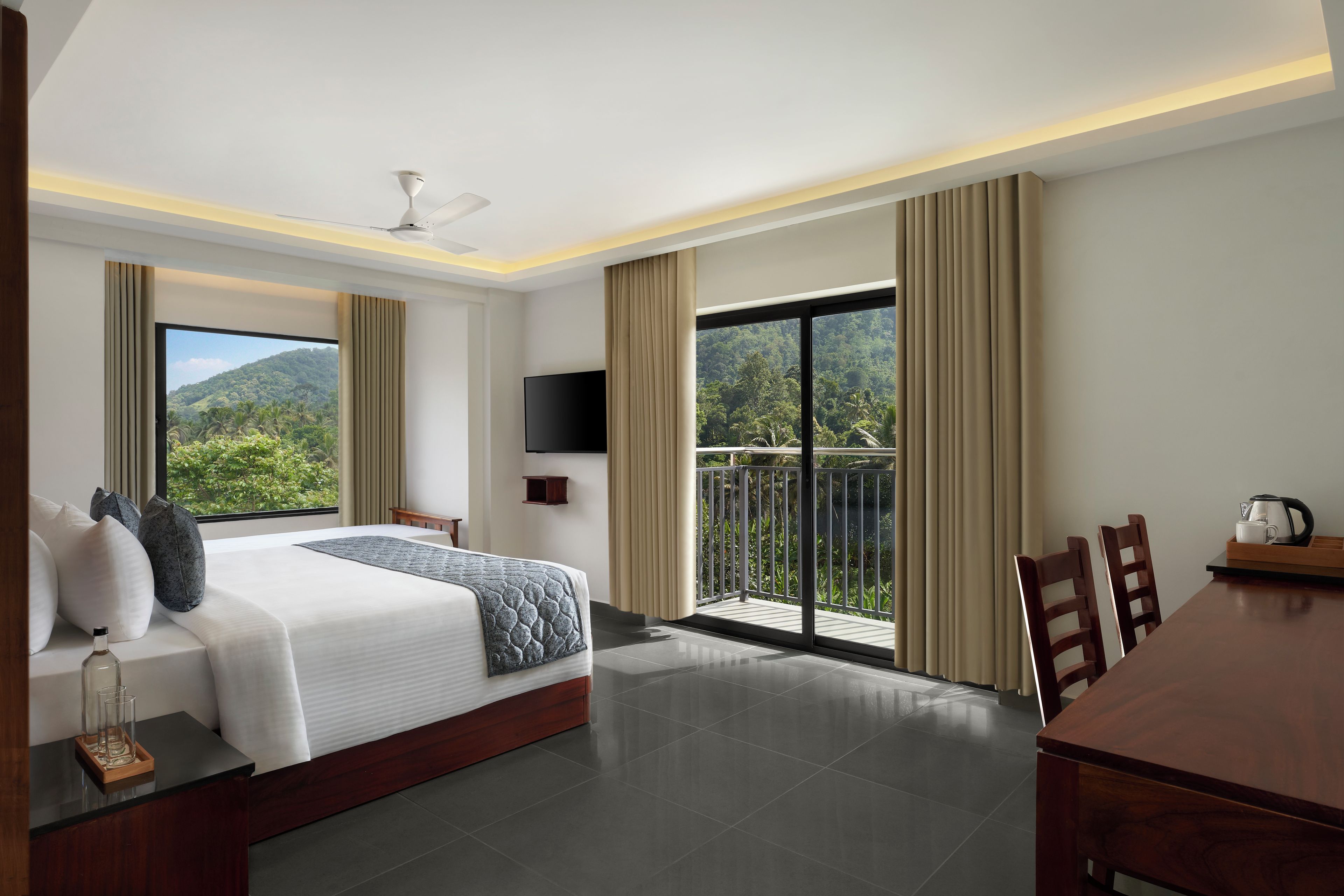A hotel room with a bed, a TV, a balcony, and a dining area.