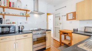 A modern kitchen with a gas stove, oven, microwave, and various appliances. - 2 Bed in Whitstable (oc-o45433) (Whitstable)