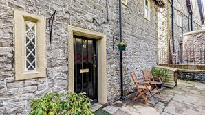 A stone building with a black door marked with the number 43, a small window with a lattice design, and a set of wooden chairs and tables outside. - 3 Bed in Cressbrook (oc-s45544) (Cressbrook)