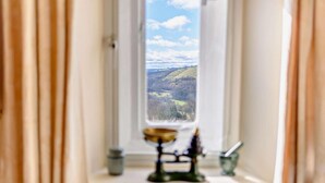 A window with a view of a landscape, a candle holder, and a small table with a candle. - 3 Bed in Cressbrook (oc-s45544) (Cressbrook)