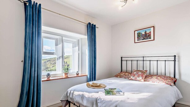 A bedroom with a bed, a window with curtains, a bedside table with a plant, and a framed picture on the wall. - 3 Bed in Cressbrook (oc-s45544) (Cressbrook)