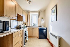 A compact kitchen with wooden cabinets, a microwave, a toaster, and a dishwasher. - 3 Bed in Cressbrook (oc-s45544) (Cressbrook)