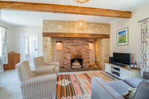 A living room with a stone fireplace, a television, and a patterned rug. - 3 Bed in Marnhull (oc-o45408) (Marnhull)