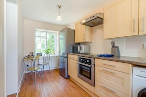 A compact kitchen with a dining area, wooden cabinets, a built-in oven, and a washing machine. - 3 Bed in Marnhull (oc-o45408) (Marnhull)