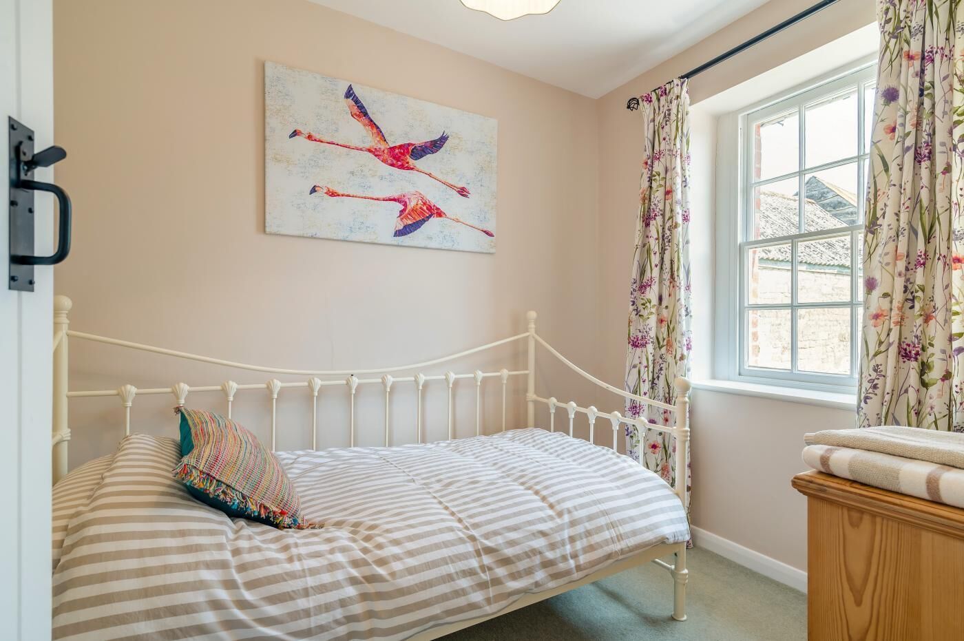 Una camera da letto con un letto, un quadro, una finestra con tende e un comò in legno.