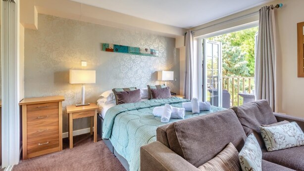 A hotel room with a bed, two bedside tables, a sofa, and a view of the outdoors. - 1 Bed in Berrier (oc-g45742) (Hutton)