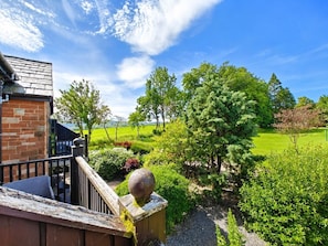 Ein Wohngebäude mit Backsteinfassade, einer Holztreppe und Blick auf eine grüne Landschaft mit Bäumen und einem Golfplatz.