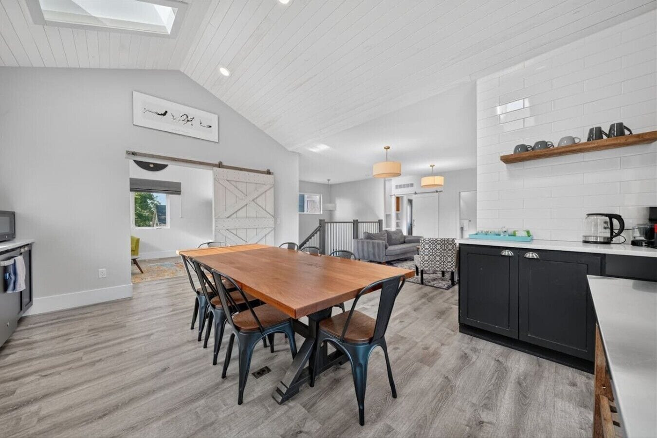 A modern kitchen with a wooden dining table, black cabinets, and a kitchen island.