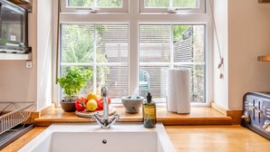 Een keuken met een groot raam, een spoelbak, een broodrooster en een plant in een pot.