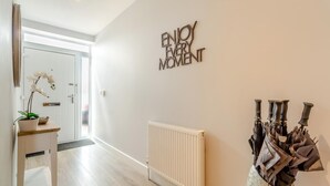 En gang med en hvid dør, en radiator og et skilte på væggen, der siger 'ENJOY EVERY MOMENT'.