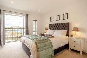 Een slaapkamer met een groot bed, een nachtkastje, een raam met jaloezieën en uitzicht op de omgeving.