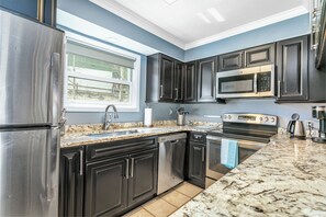 A modern kitchen with dark cabinetry, stainless steel appliances, a large window, and a marble countertop. - Great location. Your Beaver Creek + Vail Basecamp (Avon)