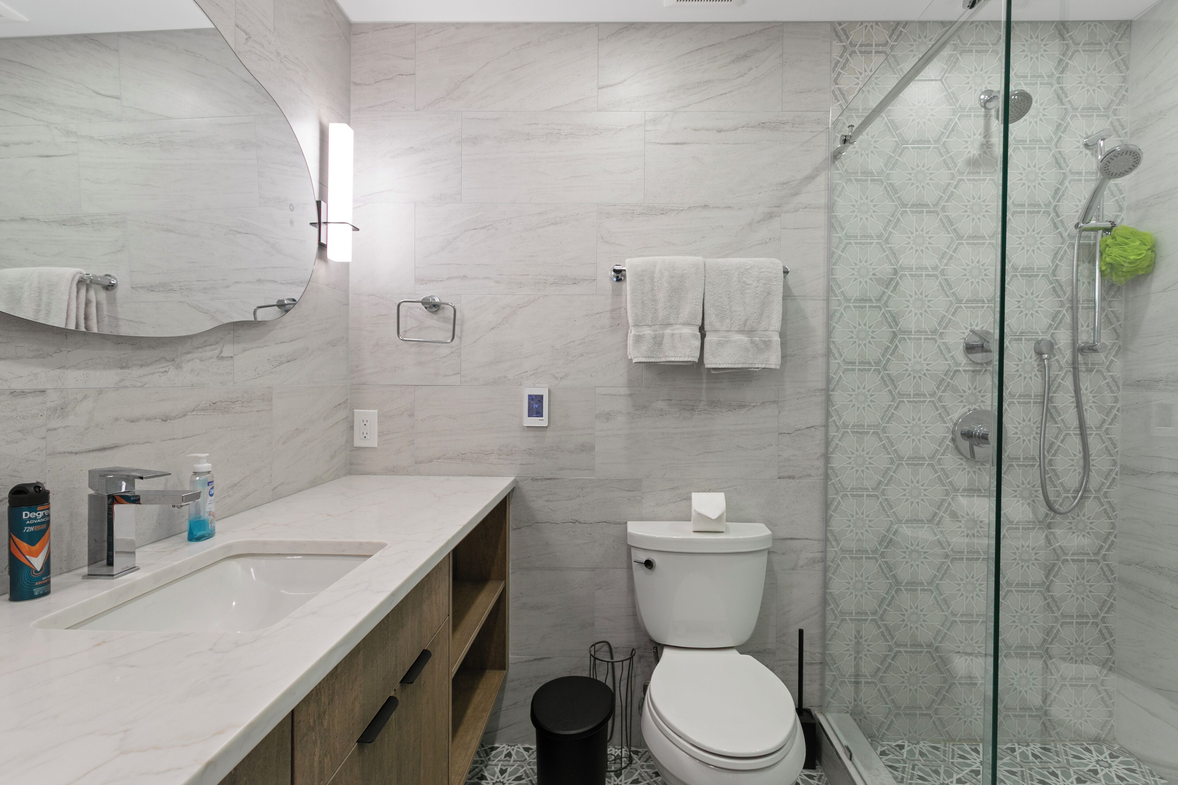 Een moderne badkamer met een marmeren wastafel, toilet en een douche met glazen wanden.